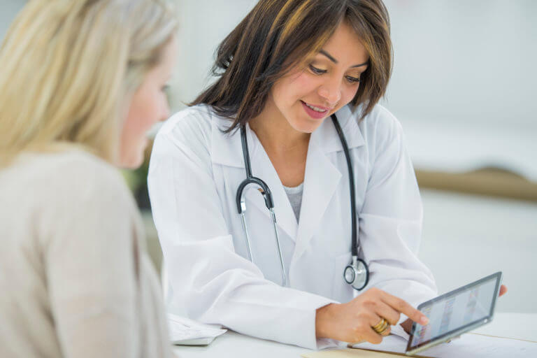 A pregnant Caucasian woman is indoors in a doctor's office