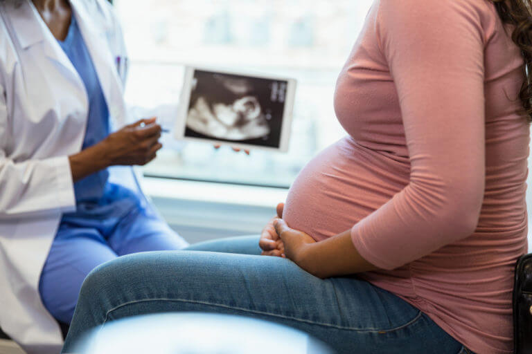 Focus on foreground as doctor shows ultrasound in background