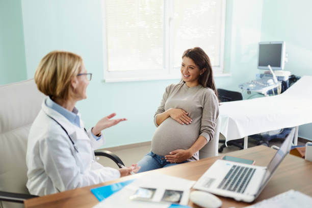 Happy expecting woman communicating with her female gynecologist during a visit in the office.